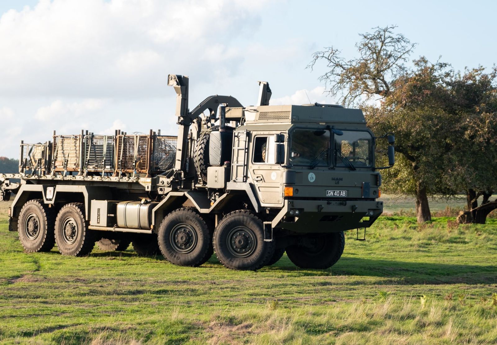 Army engineering vehicle on a rural road near a field camp