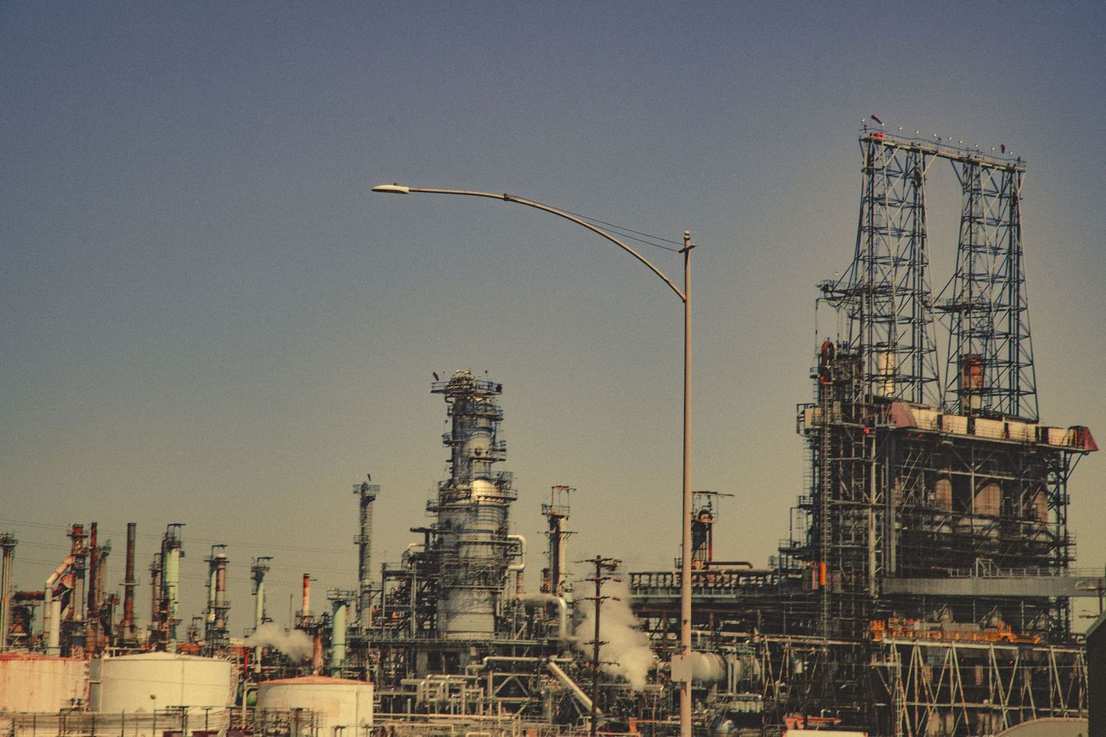 Refinery towers at dusk, where turnaround crews need beds close to the plant gate