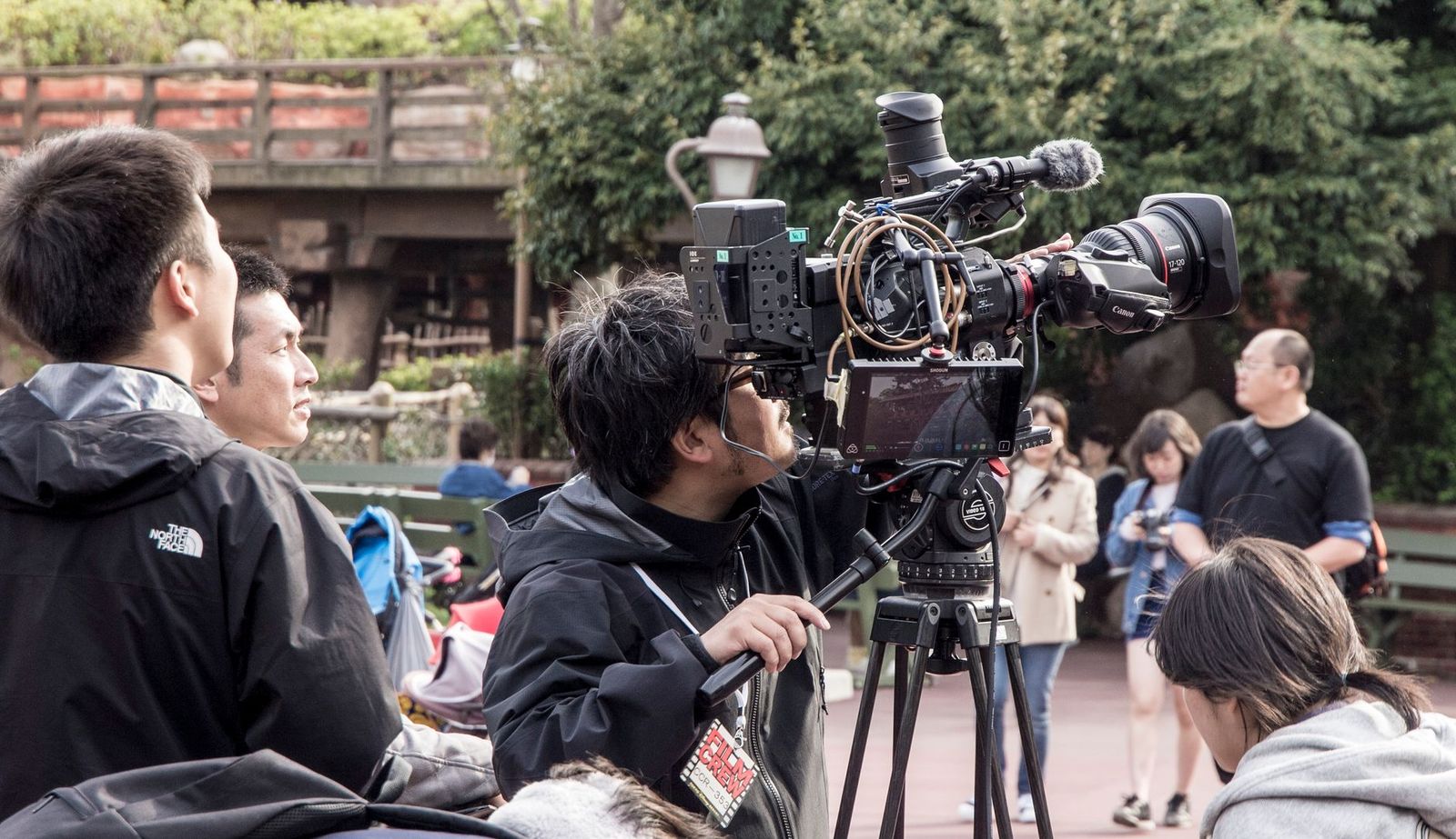 Television production crew filming under a canopy on location